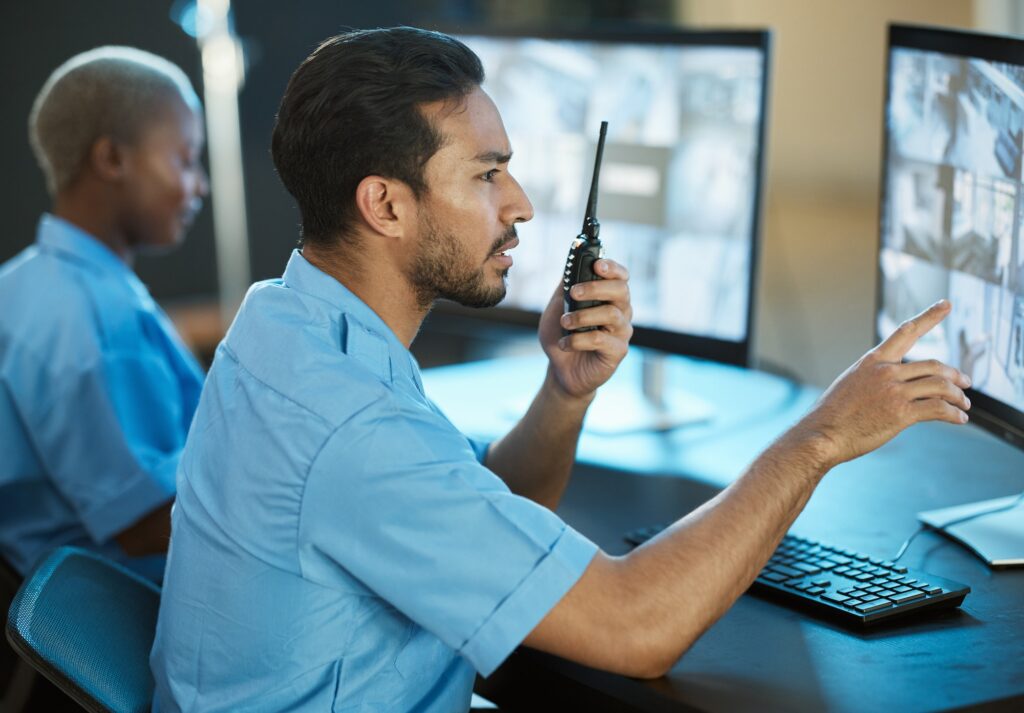 Control room, safety and security guard with a radio and computer screen for surveillance. Man and