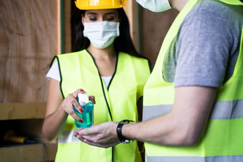 Young engineer workers use hand sanitizer gel for hand hygiene before working in warehouse factory.